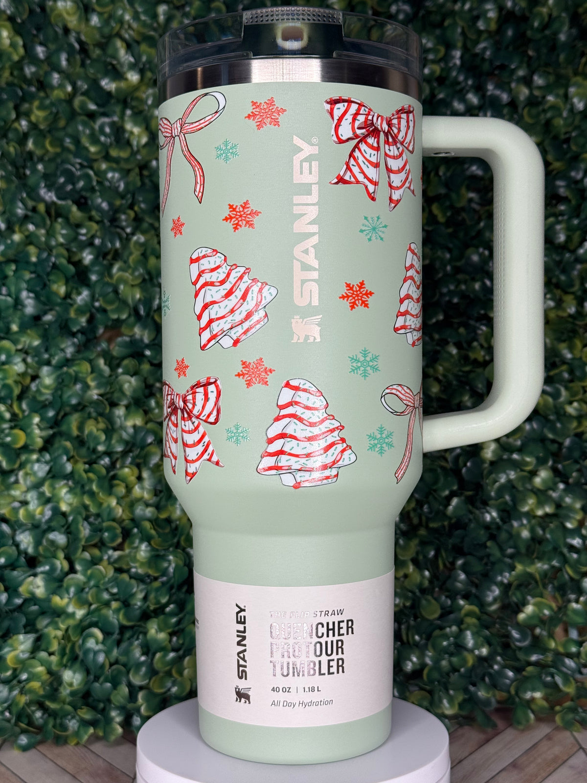 A green insulated tumbler with a handle and a label featuring Christmas-themed designs.